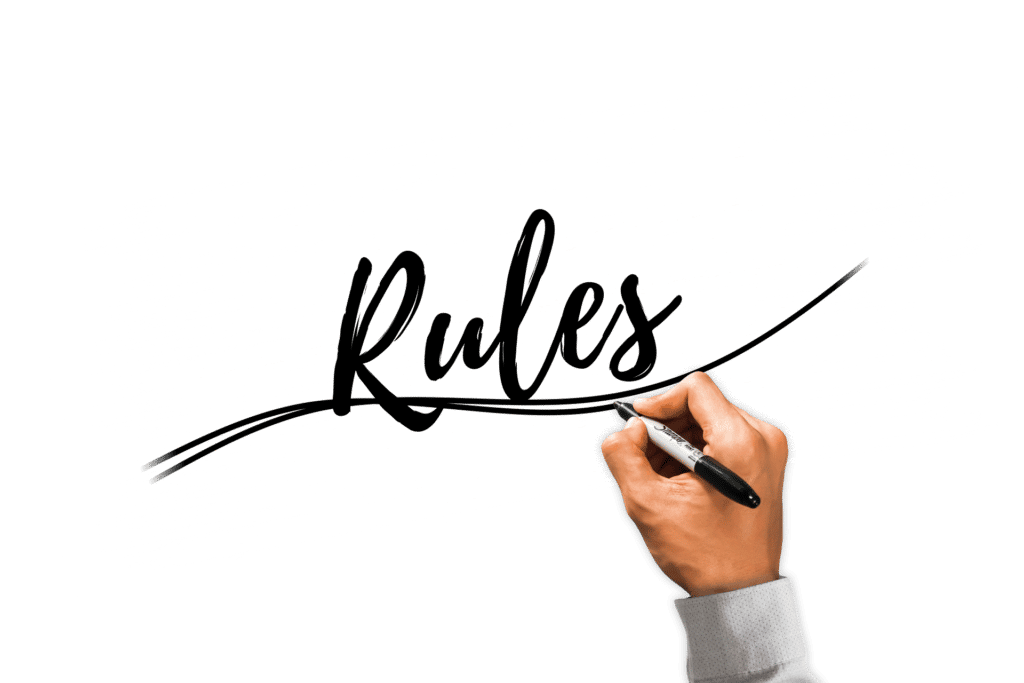 A hand using a sharpie marker to write the word "Rules" in script