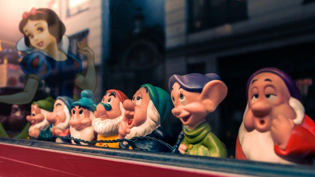 Photo of toy figurines of the seven dwarfs next to a drawing of Snow White