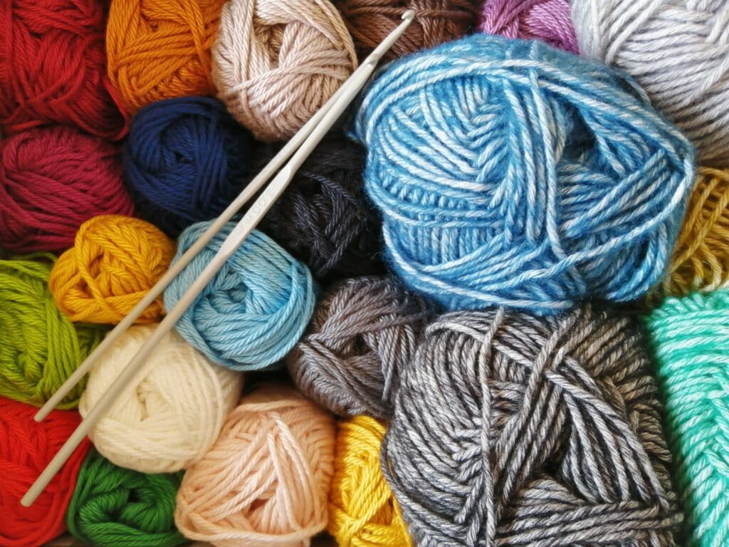 Photo of needles atop different colorful balls of yarn