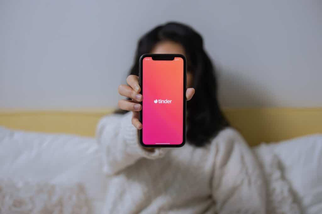 Photo of a woman showing her iPhone screen, which is displaying the Tinder app loading screen