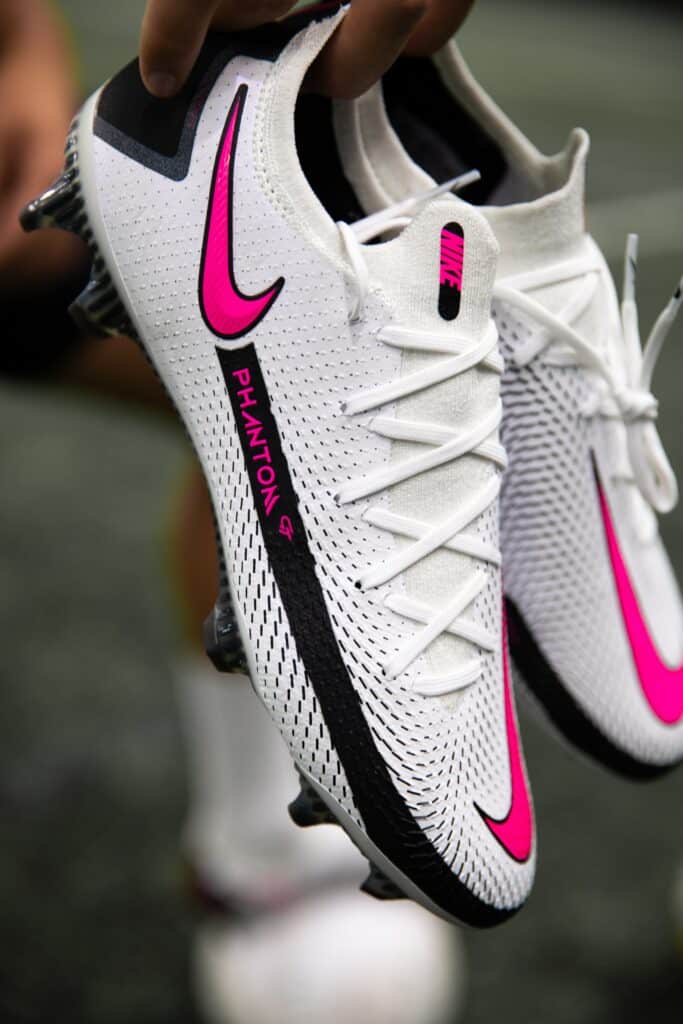 Close up photo of white and pink Nike soccer shoes