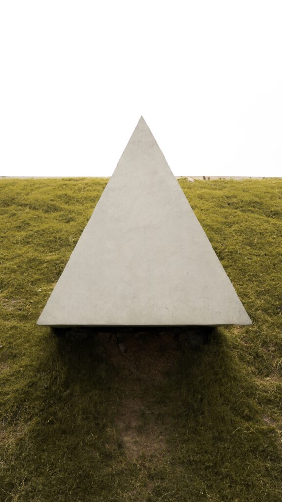 Photo of a gray concrete triangle on a grassy hill