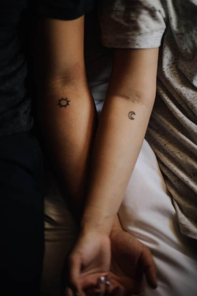 Photo of a couple's arms showing small,  matching sun and moon tattoos