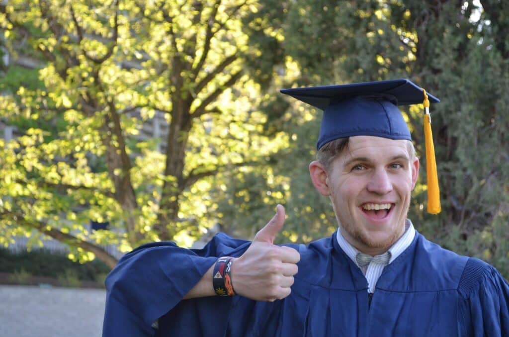 Goofy guy with this thumb up in graduation gown
