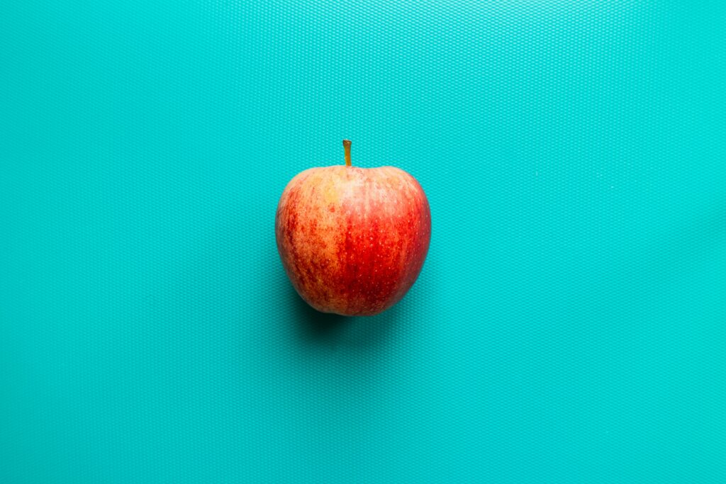Photo of a red apple against a teal background