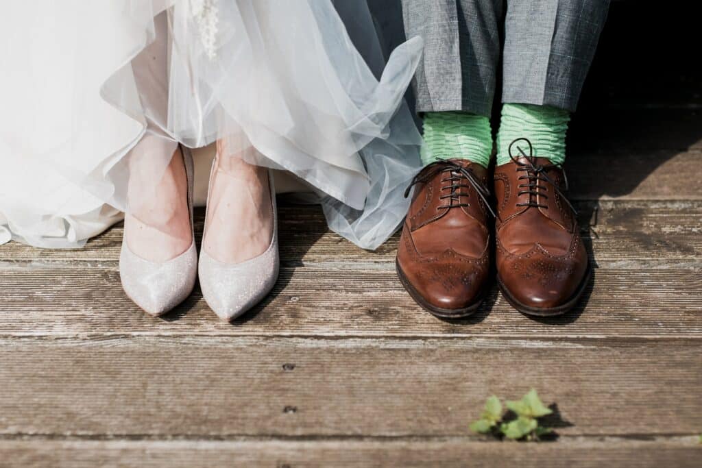 Photo of a bride and groom's shoes, sitting next to each other.