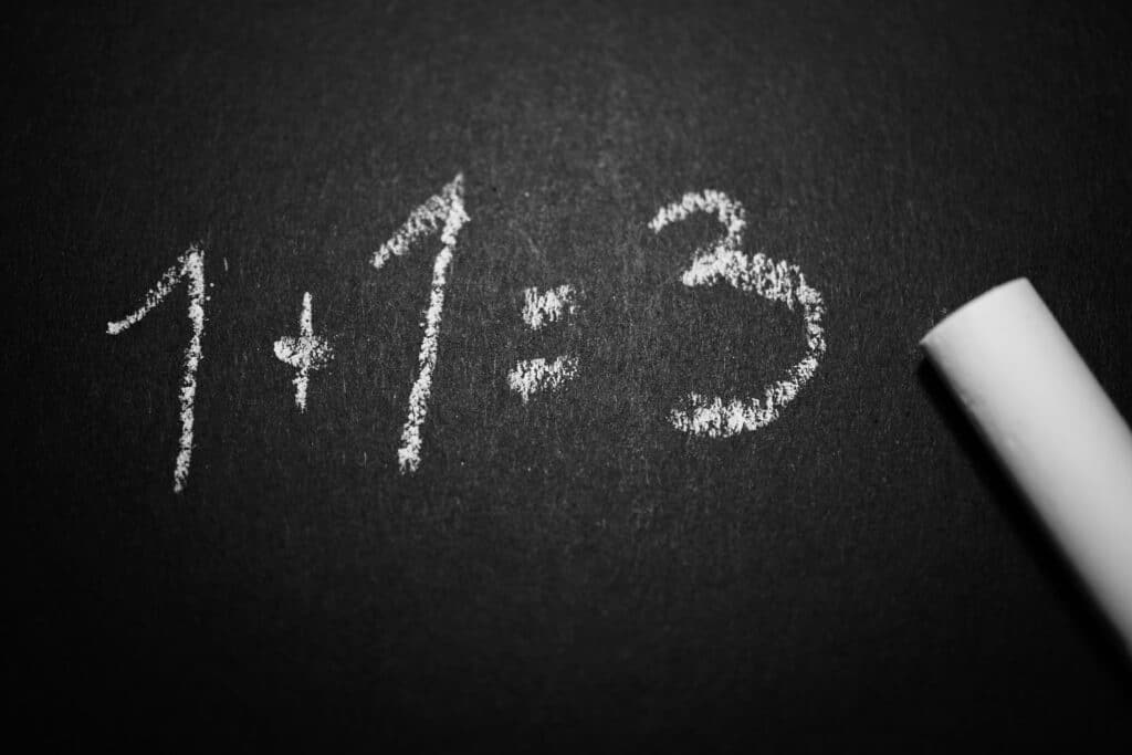 Chalk on a blackboard writing out "1+1=3"
