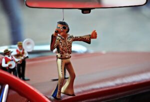 An Elvis Presley ornament hanging from the rear view mirror in a car