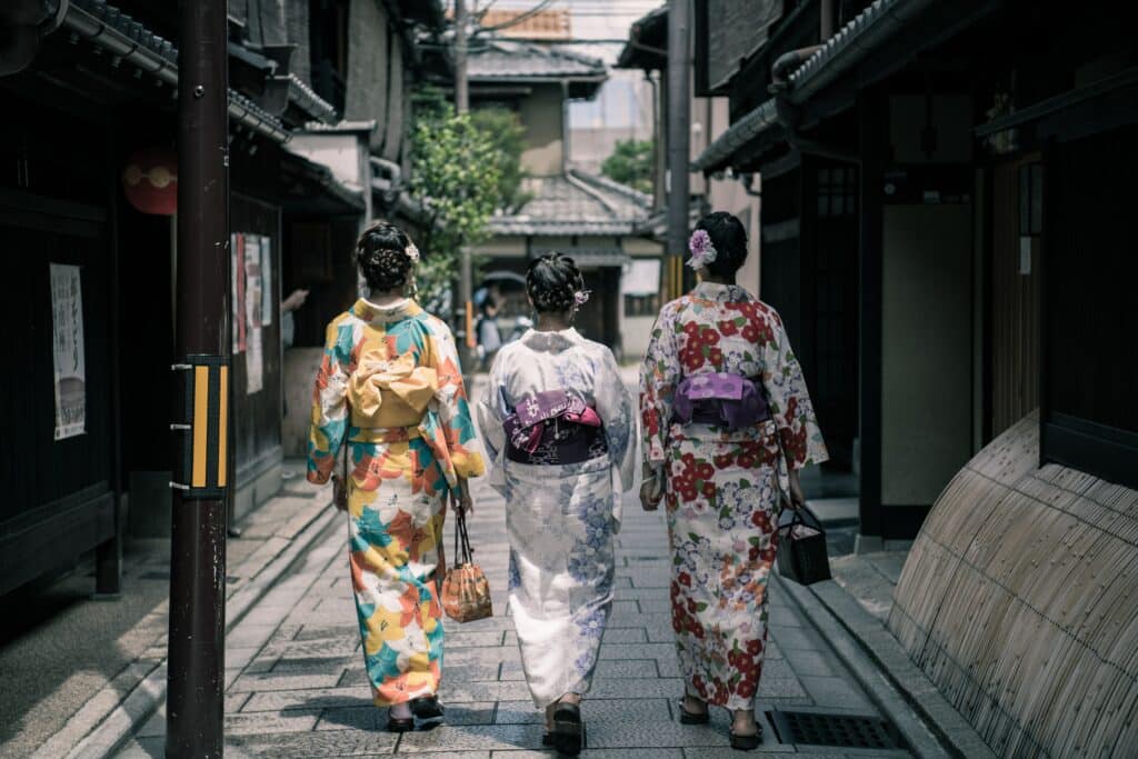 Photo of three Geisha women walking down a Japanese street from behind