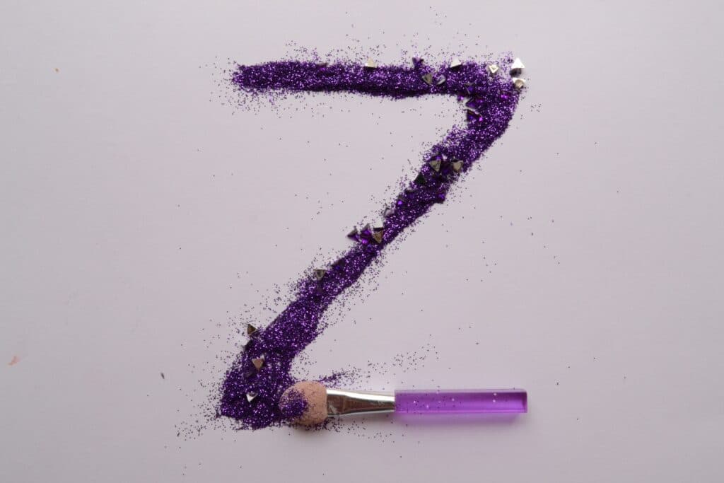 A makeup brush of purple glitter spelling out the letter Z