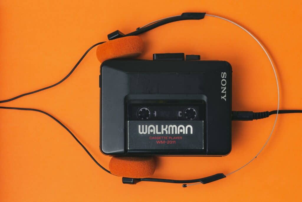 Photo of a black Sony Walkman cassette player with black and orange headphones against a bright orange background