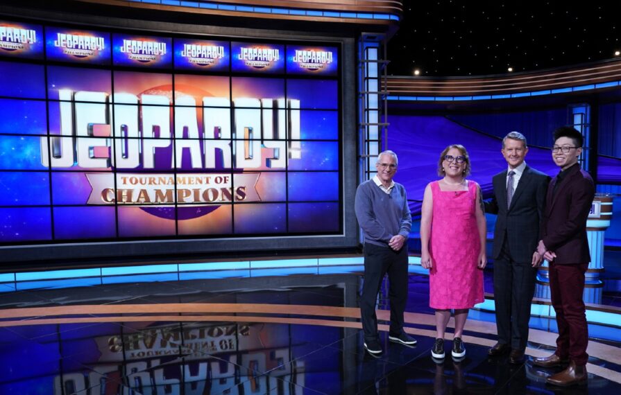 Photo of Amy Schneider alongside Andrew He, Sam Buttrey, and Jeopardy! host Ken Jennings on the Jeopardy! stage