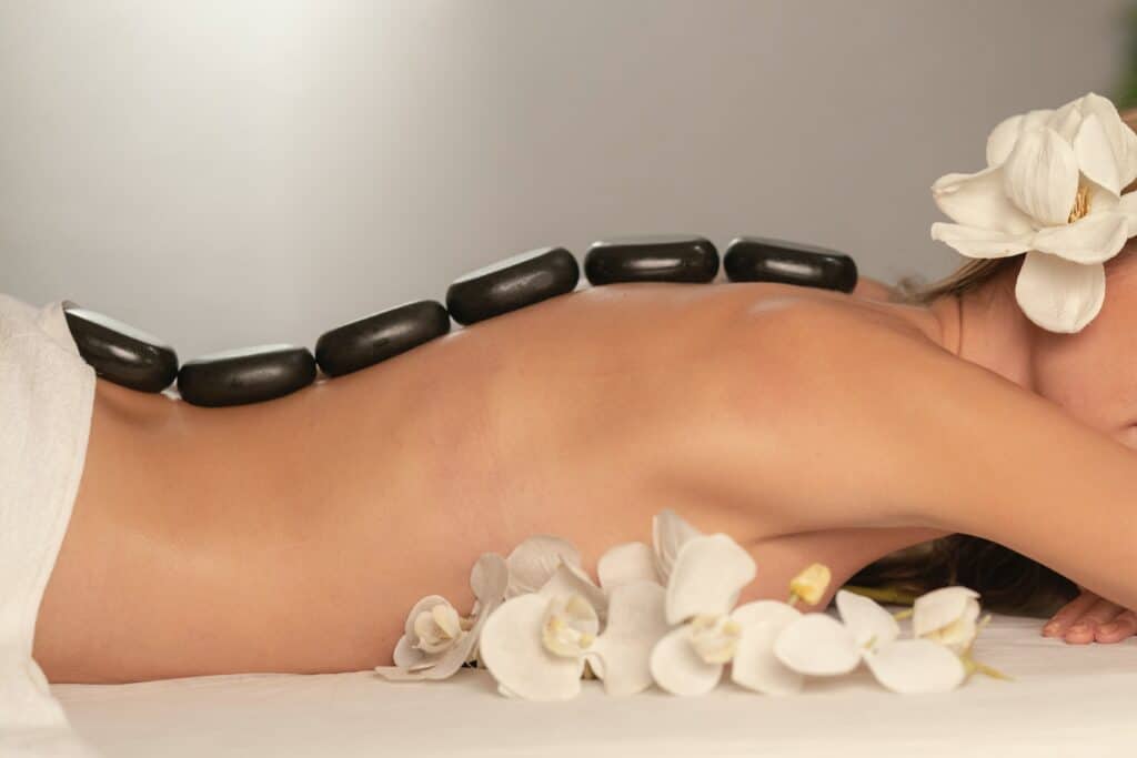 Photo of a woman at a spa with rocks down her back for a massage.
