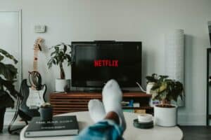 Feet up on a coffee table in front of a TV that displays "Netflix"