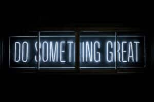 A light up sign against a black background that reads "DO SOMETHING GREAT"