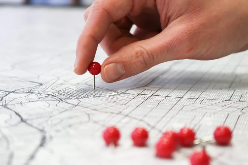 Close up of a person's hands putting a red pin on a map.