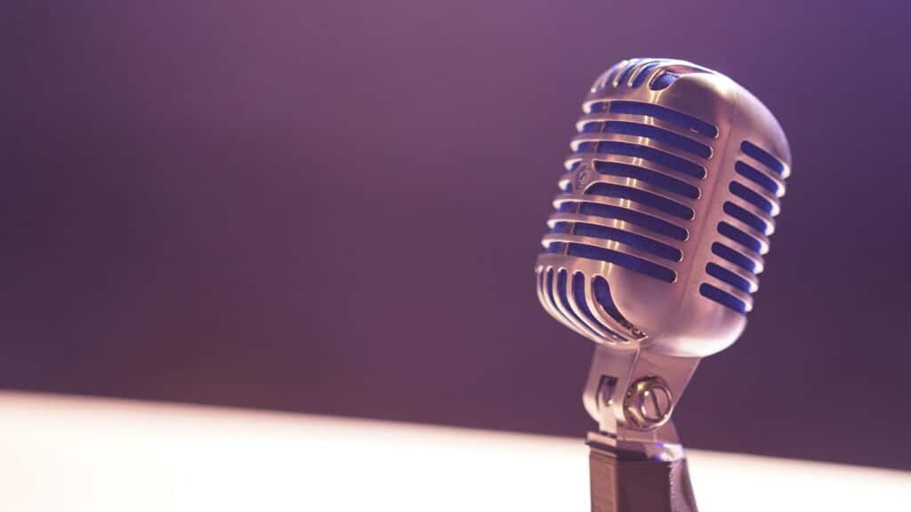 Photo of a silver microphone against a purple backdrop.