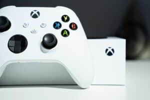 Close up photo of a white Xbox Series One with a controller leaning against it