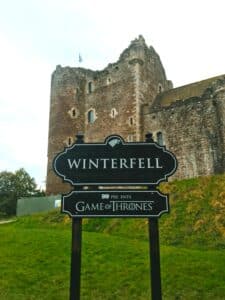 A street sign with "Winterfell" written on it, with a castle in the back