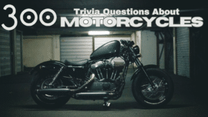 Photo of a black Harley Davidson motorcycle in a garage with grey text above it that reads "300 Trivia Questions About Motorcycles"
