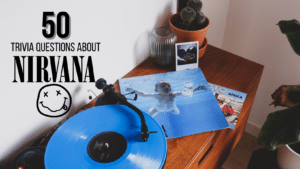 Photo of a desk with plants and a record player on it playing the blue Nirvana "Nevermind" album, with text above it in black that reads "50 Trivia Questions About Nirvana"