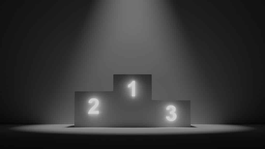 Photo of black ranking blocks numbered one, two, and three in white, under a spotlight against a black background.