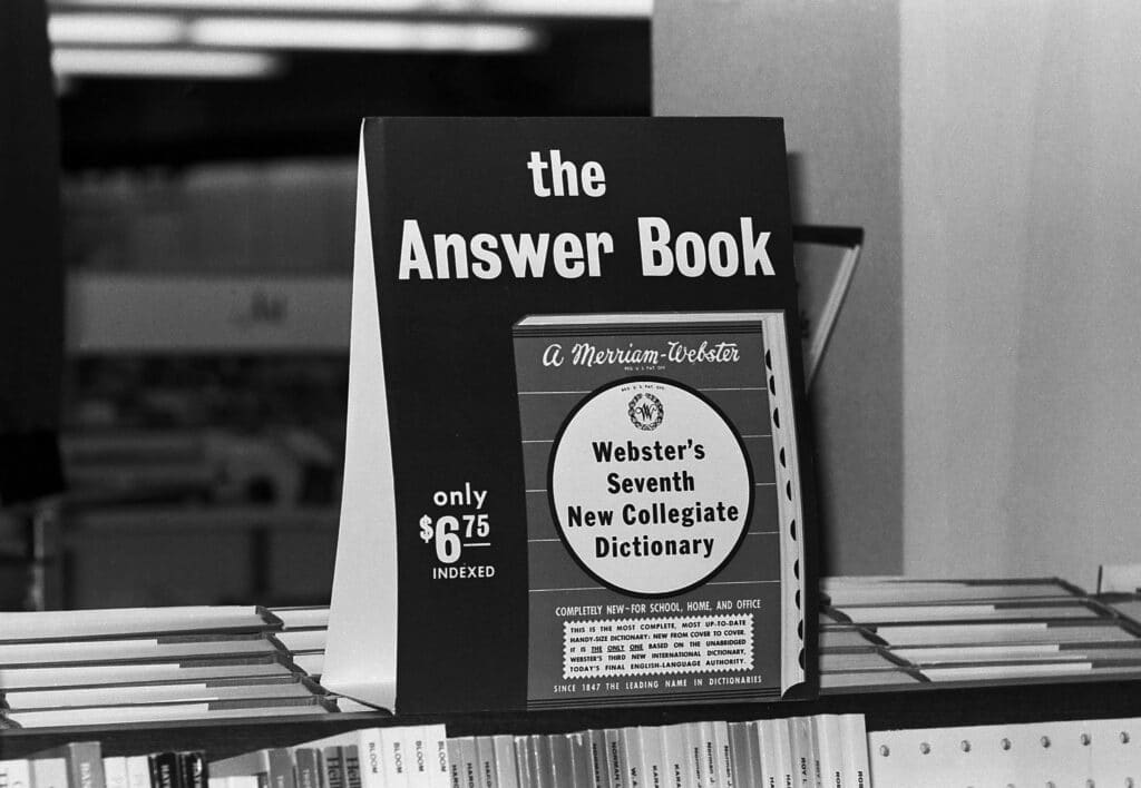 Black and white photo of an advertisement that reads "the Answer Book" for Webster's Seventh New Collegiate Dictionary.