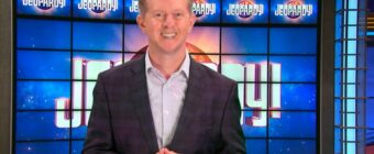 Photo of Ken Jennings standing in front of the Jeopardy! board.