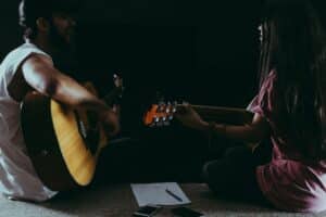 Two people playing guitar in the dark