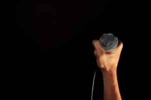 A hand holding up a microphone against a black background