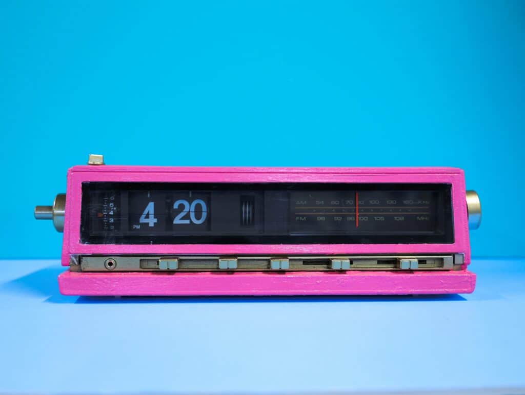 Photo of a pink clock displaying a time that reads 4:20, against a blue background.