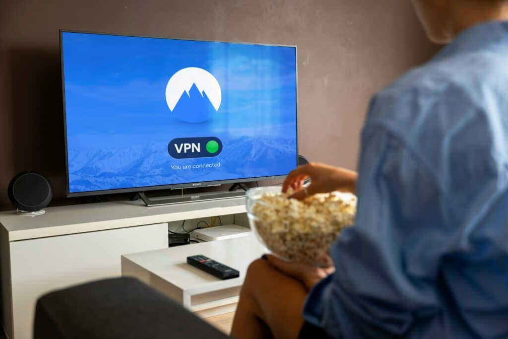 Photo of a person with a bowl of popcorn, watching a TV displaying a blue VPN screen.
