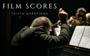 Photo of a conductor playing a piano in an orchestra, with white text in the top left corner that reads "FILM SCORES TRIVIA QUESTIONS"